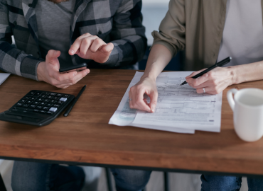 Entrepreneur working at a laptop with financial papers and tax savings illustration.